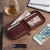 Męski portfel skórzany Wild Horse 9 ciemny brąz, otwarty na drewnianym blacie, z widocznymi przegródkami na karty, banknotami i rodzinnym zdjęciem. Obok telefon, szkło z alkoholem i notatnik.