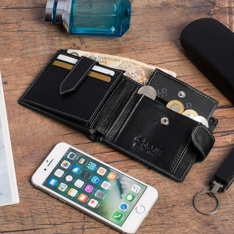 Męski portfel skórzany Wild Horse 12A czarny ziarnisty, otwarty, z widocznymi przegródkami na karty, banknotami i monetami. Na drewnianym tle leży smartfon i brelok.